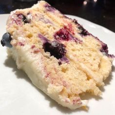 a piece of cake with blueberries and cream on it sitting on a white plate