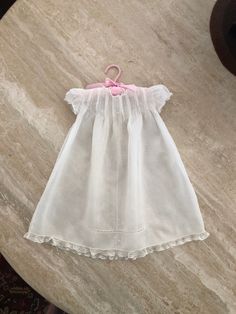 "A vintage batiste baby christening dress. It features lace at the neckline and edging the short sleeves. There are 8 rows of tucks across the bodice with dainty embroidery between. Small floral sprigs cascade down the front meeting a horizontal band of lace. The bottom edge is trimmed with lace. Both sides have an inverted pleat below the sleeve. The back has 6 rows of tucks and a 3 button closure. NOTE: There is a small tear near the bottom (See last photo) Measurements:    13\" across front under the sleeves    20\" in length from shoulder to bottom" Classic Short Sleeve Baptism Dress With Ruffles, Summer Baptism Dress With Lace Trim, Classic Ruffles Baptism Dress, White Short Sleeve Baptism Dress For Daywear, White Baptism Dress With Short Sleeves For Daywear, Classic Ruffled Baptism Dress, Short Sleeve Dress With Lace Trim For Baptism, Summer Baptism Dress With Short Sleeves, Fitted Short Sleeve Baptism Dress With Ruffles