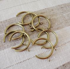 several brass colored rings sitting on top of a beige table cloth covered with white linen