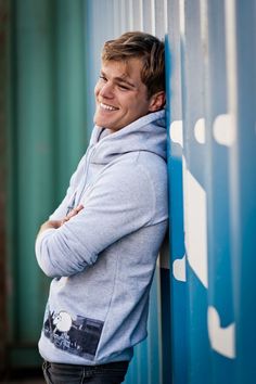 a young man leaning against a blue wall