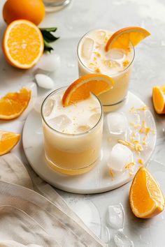 two glasses filled with orange juice on top of a white plate