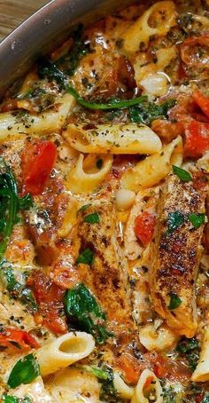 a pan filled with pasta and vegetables on top of a wooden table