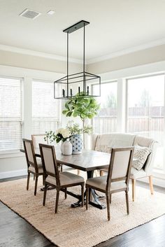 a dinning room table with chairs and a vase on the rug in front of it