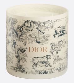 a white candle with an image of animals on it and the word dior written in gold