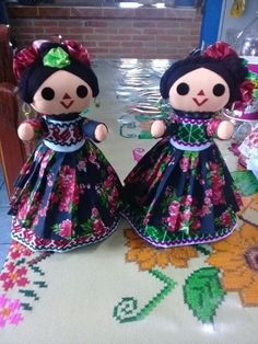 two dolls sitting on top of a table next to each other