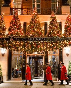 people walking in front of a building decorated with christmas trees