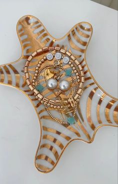 a gold and white star shaped brooch with pearls on it's center piece