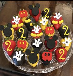 mickey mouse cupcakes are arranged in the shape of numbers on a glass plate