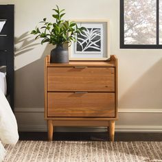 a bedroom with a bed, nightstand and plant on top of the dresser next to it