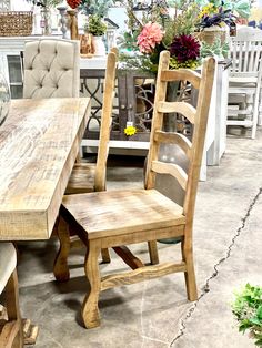 two wooden chairs sitting next to each other in front of a table with flowers on it