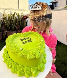 a woman holding a green cake with the words baby b'day written on it