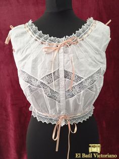 This Edwardian-style corset cover is made in 100% cotton voile. It is trimmed with lace insertion, creating a diamond pattern across the chest. The fronts are gathered at the waist, to create that pigeon bust effect so prevalent of the period. At the back, it has eight small darts to give some shape. At the neckline in front and the armsyce on the back it is trimmed with very fine pintucks. The neckline, waistline and armholes are trimmed with beading lace, so they can be drawn and adjusted. It Underbust Lace Bodice With Lace Trim, White Underbust Bodice With Lace Trim, Feminine Underbust Corset With Lace Trim, Fitted Sleeveless Bodice With Lace Trim, Vintage Lace Corset With Lace Trim, Vintage Lace Overbust Bodice, Vintage Corset With Lace Trim, White Lace Vintage Corset, White Vintage Lace Corset