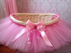 a pink tutule and bow sits in a wicker basket on the floor