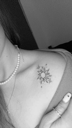 a black and white photo of a woman's chest with a sun tattoo on it