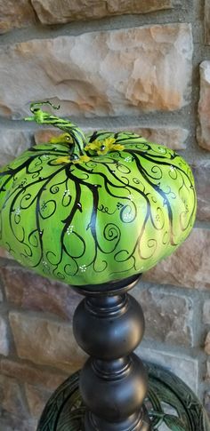 a green and black lamp sitting on top of a metal stand next to a brick wall