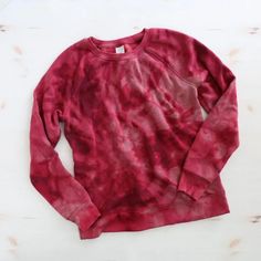 a red tie - dyed sweatshirt sitting on top of a white table