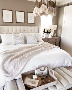 a white bed sitting in a bedroom under a chandelier