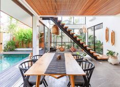 an outdoor dining area next to a pool with stairs leading up to the second floor