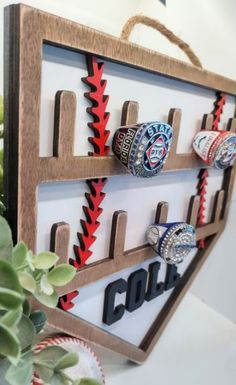 a wooden sign with baseballs and rings hanging from it's sides on a shelf