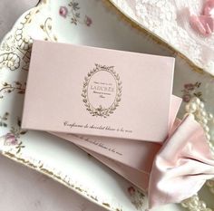 two folded pink cards sitting on top of a table next to lace doily and flowers