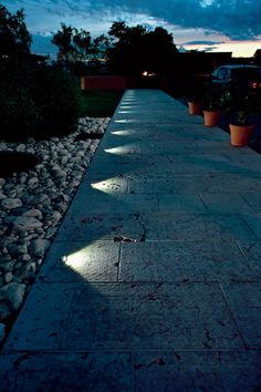 an empty sidewalk with potted plants next to it at night in front of a building