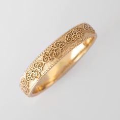 a gold wedding band with filigrees and hearts on the inside of it