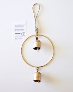 a bell hanging from a ring on a white wall next to a piece of paper