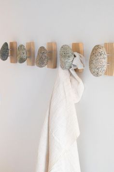 the towel rack is made out of wood and has three rocks on it, along with two towels