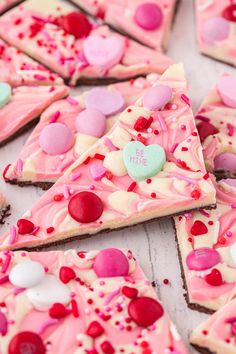 valentine's day desserts are arranged on a white table with pink icing