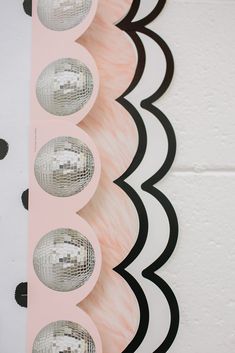 three disco balls are sitting on top of a pink and black wallpapered background