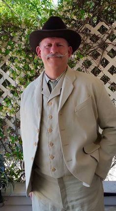 a man in a suit and hat poses for a photo