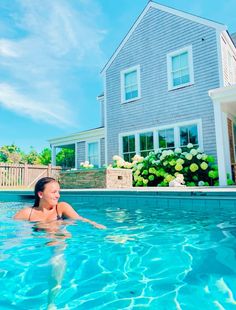 a woman in a swimming pool next to a house