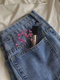 a flower sticking out of the pocket of a pair of jeans on top of a bed