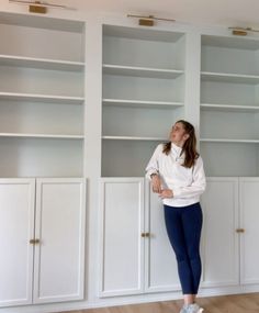 a woman standing in front of white bookcases