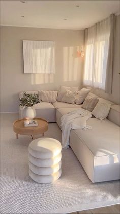 a living room filled with lots of white furniture and decor on top of carpeted flooring