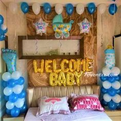 a baby shower party with balloons and welcome baby sign on the wall above the bed