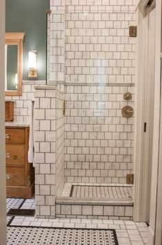 a bathroom with white tile and black and white flooring