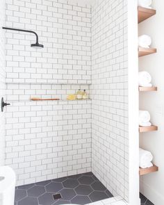 a white tiled shower with shelves and towels