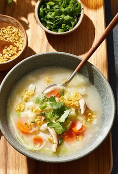 a bowl filled with soup next to two bowls full of vegetables and other food items