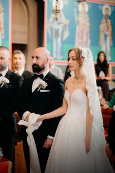 the bride and groom are walking down the aisle at their wedding ceremony, with other people in the background