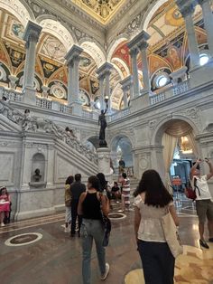 many people are walking around in an ornately decorated building with marble floors and ceilings