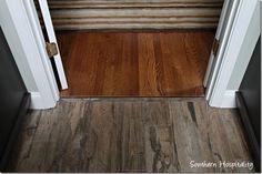 an open door leading to a hallway with wood floors and striped rug on the floor