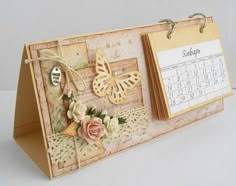 a desk calendar with flowers and butterflies on it, attached to a wooden holder that holds a clipboard