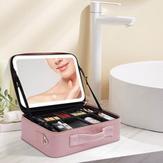 an open pink suitcase sitting on top of a white counter next to a sink and mirror