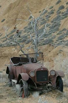 an old rusted out car in the middle of nowhere