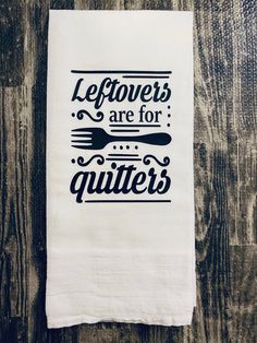 a tea towel with the words leftovers are for quitters printed on it, sitting on a wooden surface