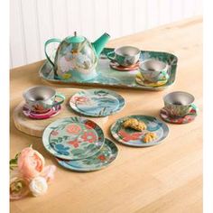 a tea set on a wooden table with plates and cups