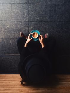 a person sitting on the floor with a cup of coffee in front of their face