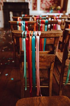 rows of wooden chairs with colorful ribbons tied to the back of them in front of a fireplace