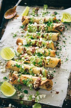 some food is laying out on a baking sheet with limes and other toppings